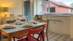 A dining area with a table set for two, a radio, and a lamp on a nightstand. - 2 bedroom accommodation in Stoke-on-Trent (Stoke-on-Trent)