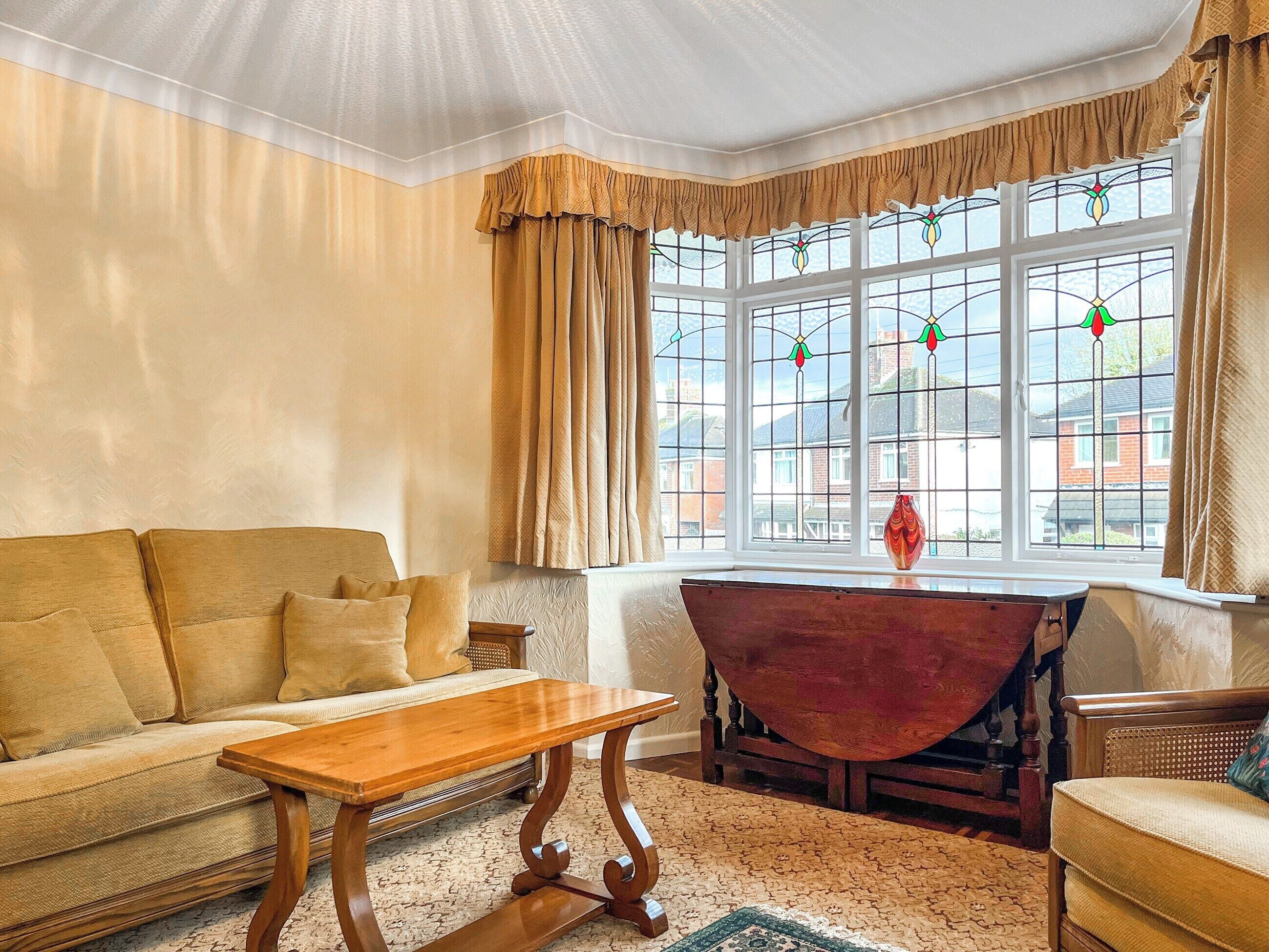 A cozy living room with a sofa, a wooden coffee table, and a red armchair.
