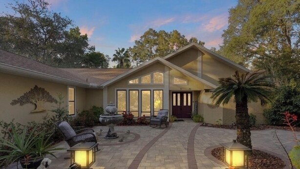 A house with a patio area, outdoor seating, and a well-maintained garden. - Luxury Heated Pool • Game Room • Near Springs & Manatees (Beverly Hills)