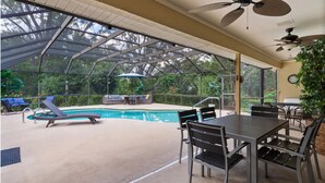 A covered outdoor pool area with lounge chairs, a table, and ceiling fans. - Luxury Heated Pool • Game Room • Near Springs & Manatees (Beverly Hills)