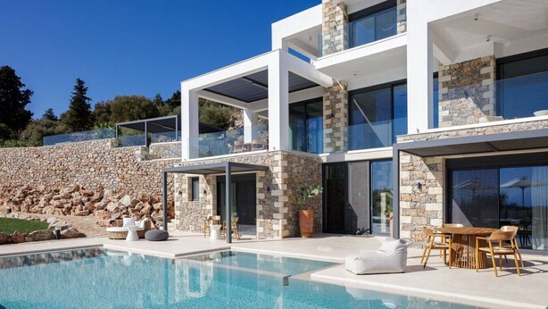 A modern two-story house with a swimming pool, stone walls, and outdoor seating. - Agapanthus Ultimate Luxury Villa (Likotinarea)