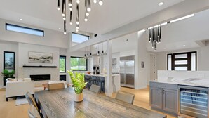 Ett modernt kök med en central köksö, rostfria vitvaror och en matplats med ett träbord och stolar.