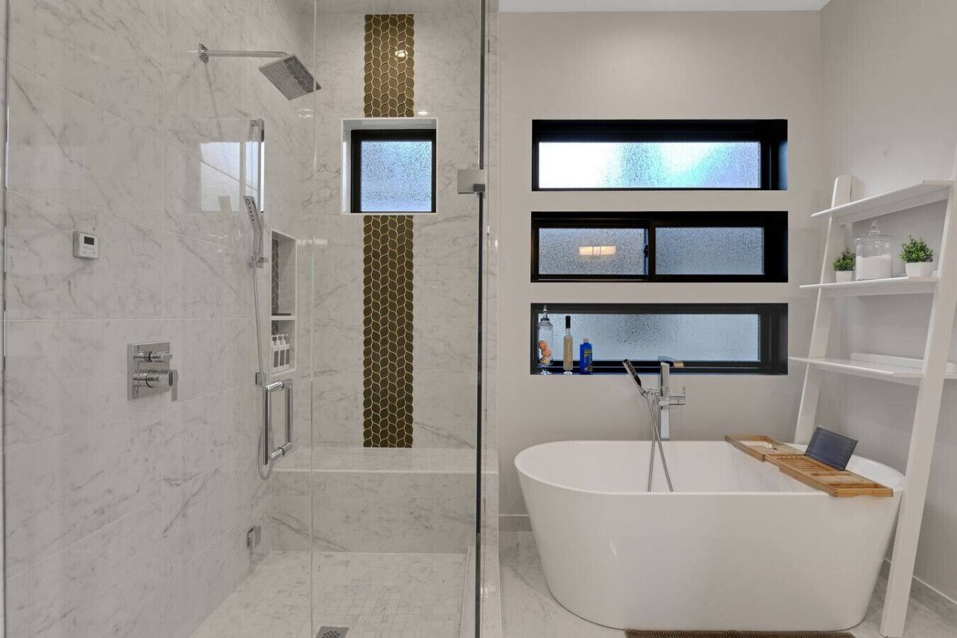 Un baño moderno con una bañera independiente, una ducha con cerramiento de vidrio y un lavamanos con ventana.