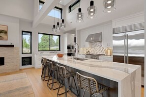 Cocina amplia con una isla grande, taburetes de bar, chimenea y vistas al exterior.