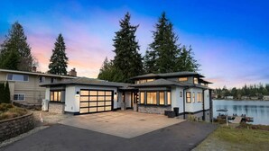 Ett tvåvåningshus med garage, en inglasad uteplats och utsikt över en sjö.