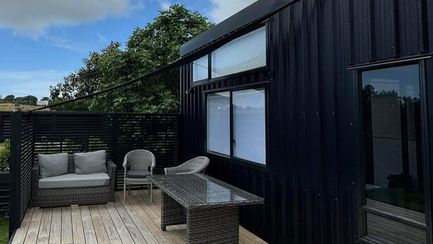 Eine Terrasse mit Korbmöbeln, darunter eine Couch und Stühle, sowie ein Tisch mit Glasplatte.