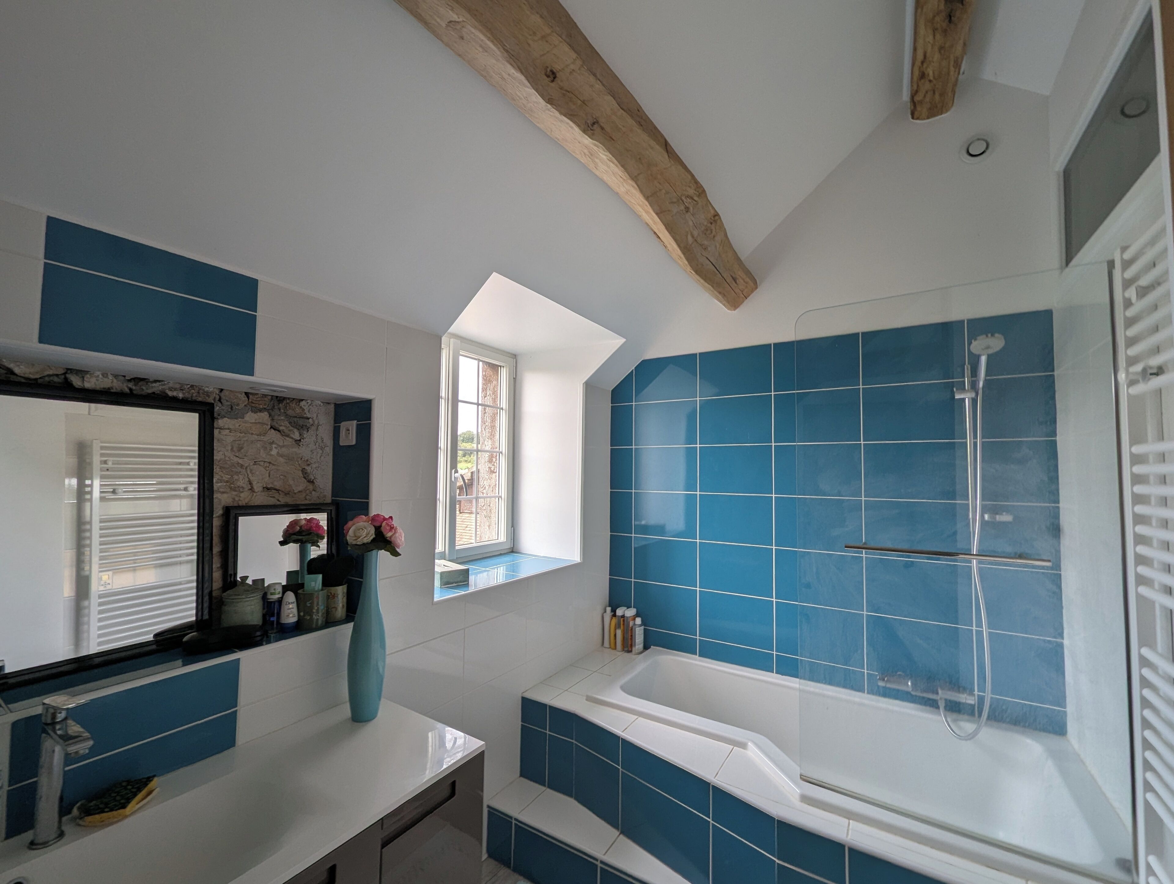 A bathroom with a bathtub, a window, and a mirror.