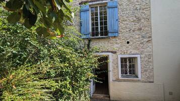 A rustic stone building with a wooden door and a window with a metal grill.