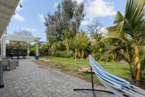 A patio area with a pergola, outdoor furniture, and a hammock. - Wheels, Waves & Game Night Retreat (Oceanside)
