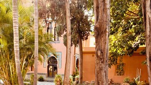 A courtyard with a checkered pool, palm trees, and a building with arched doorways. - Casita Mezcal, in City Center With Great Views (Almunecar)