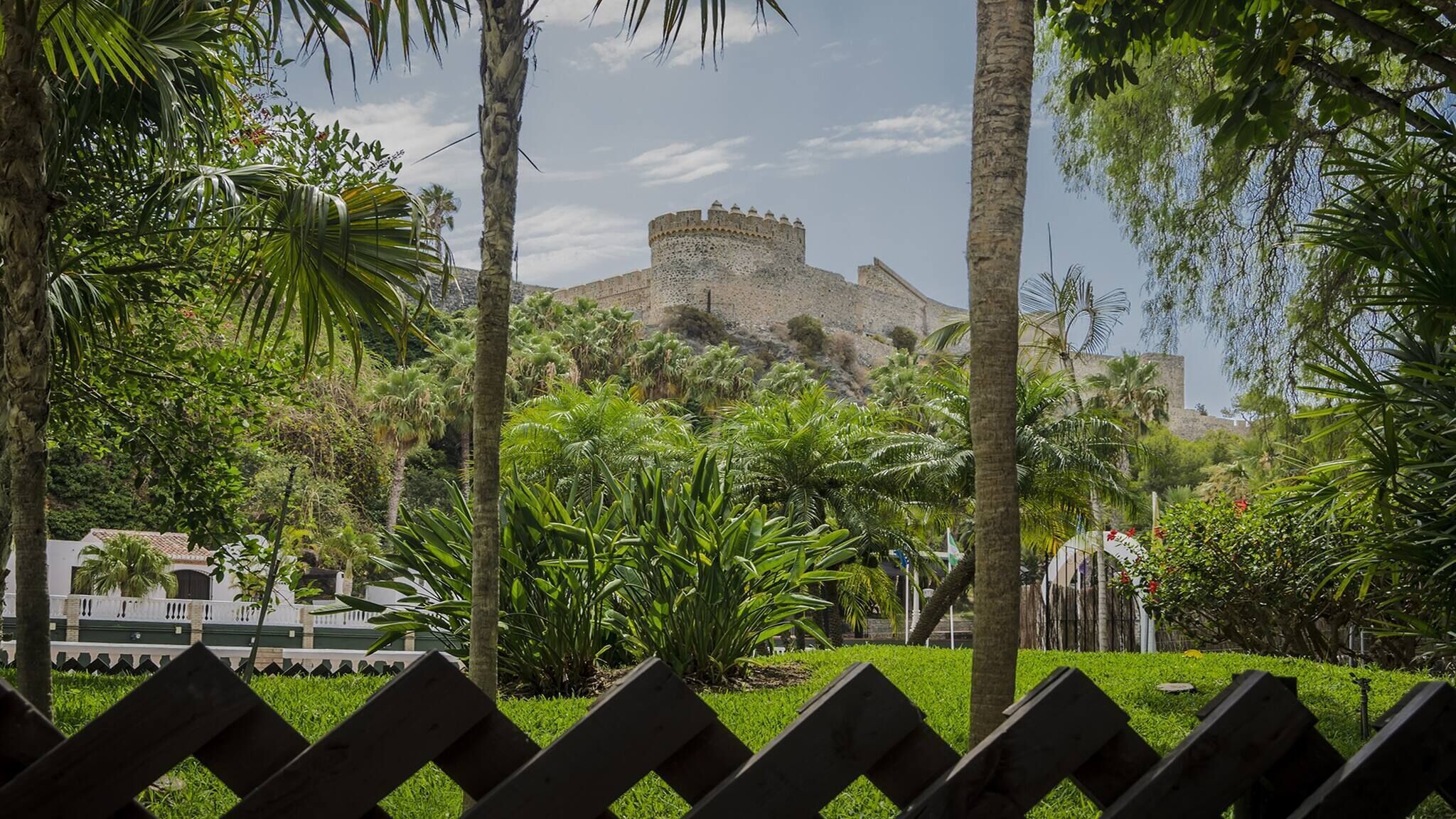 A historic fort surrounded by lush greenery and palm trees.
