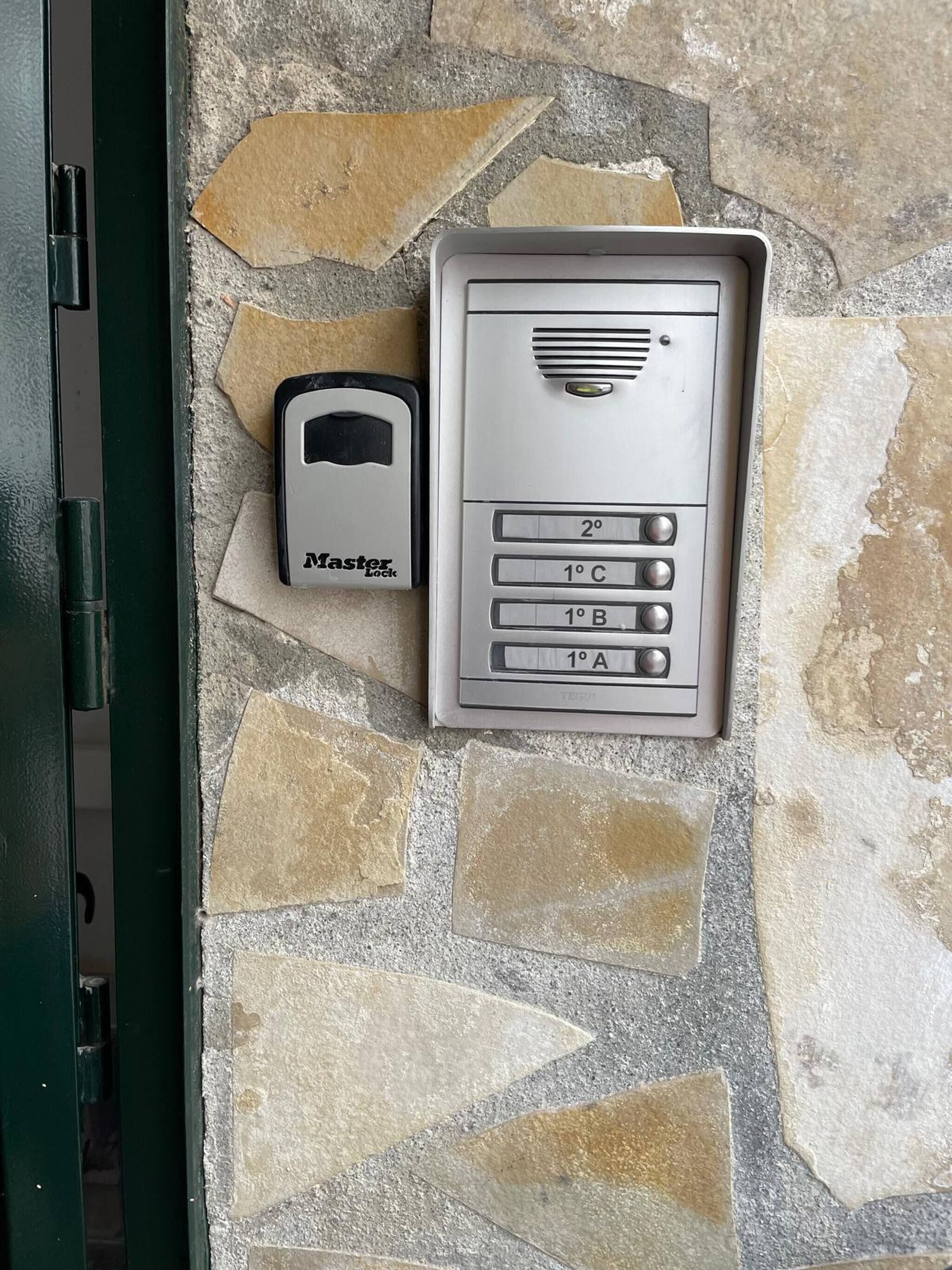 Een keypaddeurslot en een Master Lock-apparaat bevestigd aan een stenen muur.