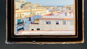 A window with a view of a coastal cityscape, including buildings and a distant hill. - Casita Mezcal, in City Center With Great Views (Almunecar)