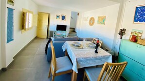 A dining area with a table set for four, a television, and a staircase leading to another level. - Casita Mezcal, in City Center With Great Views (Almunecar)