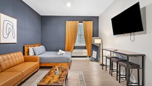 Een moderne hotelkamer met een bank, bed, salontafel en een aan de muur bevestigde televisie.