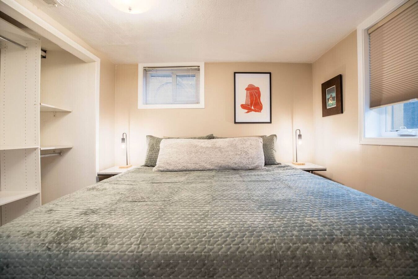 A bedroom with a bed, a window, a framed picture, and a wardrobe.