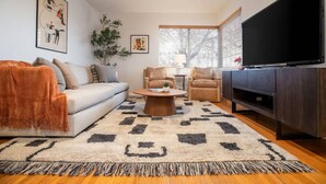Una sala de estar moderna con un sofá, sillones, una mesa de centro y un televisor.
