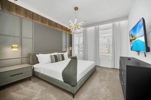 Une chambre moderne avec un grand lit, une télévision et une commode.