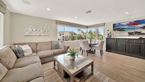 A spacious living room with a large window, a dining area, and a kitchen with dark cabinetry.