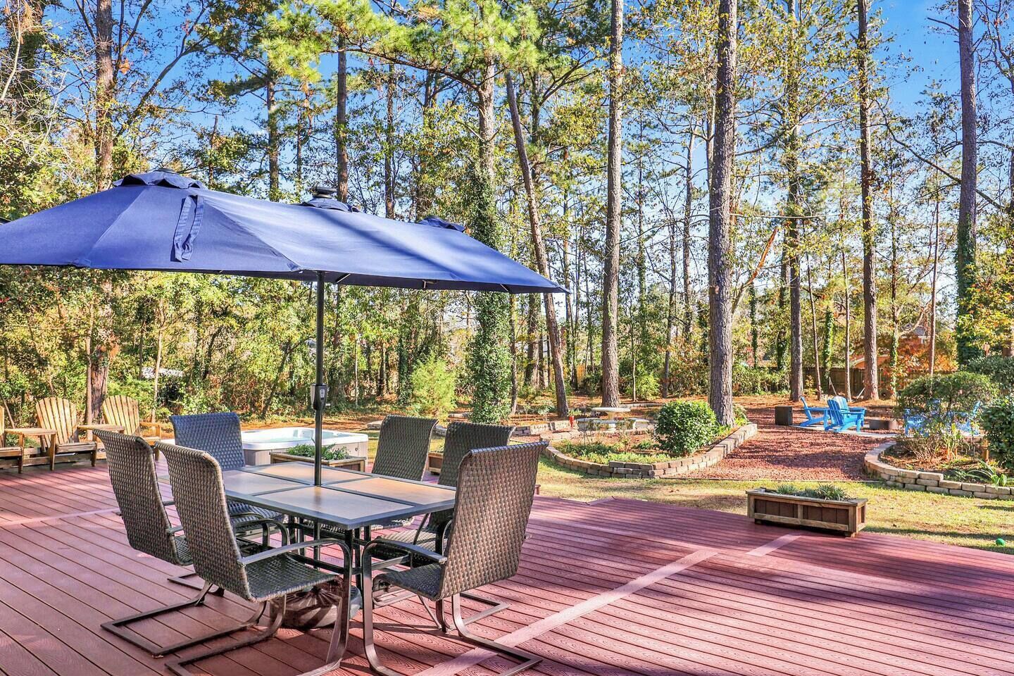 A deck with outdoor furniture, a table, and a blue umbrella.