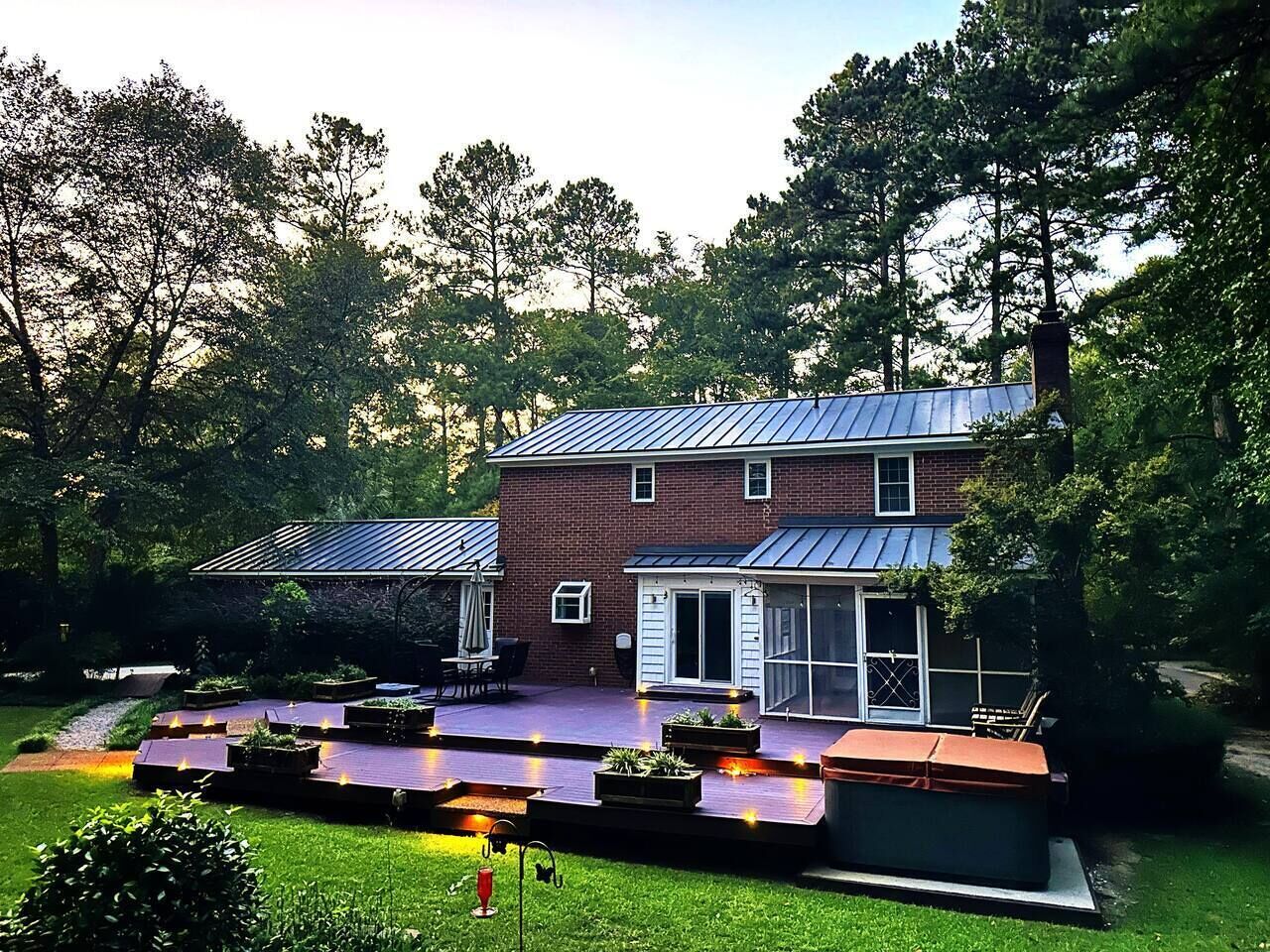 A two-story brick house with a covered patio, a screened porch, and a small attached garage.