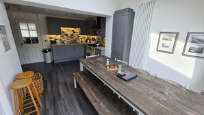 Una cocina moderna con armarios oscuros, una mesa de comedor de madera y vistas al área de comedor contigua.
