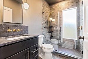 Ein modernes Badezimmer mit Marmorwaschtisch, Toilette und einer Duschkabine.