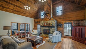 L’intérieur d’un chalet rustique, avec une cheminée en pierre, un plancher en bois et un coin salon confortable.