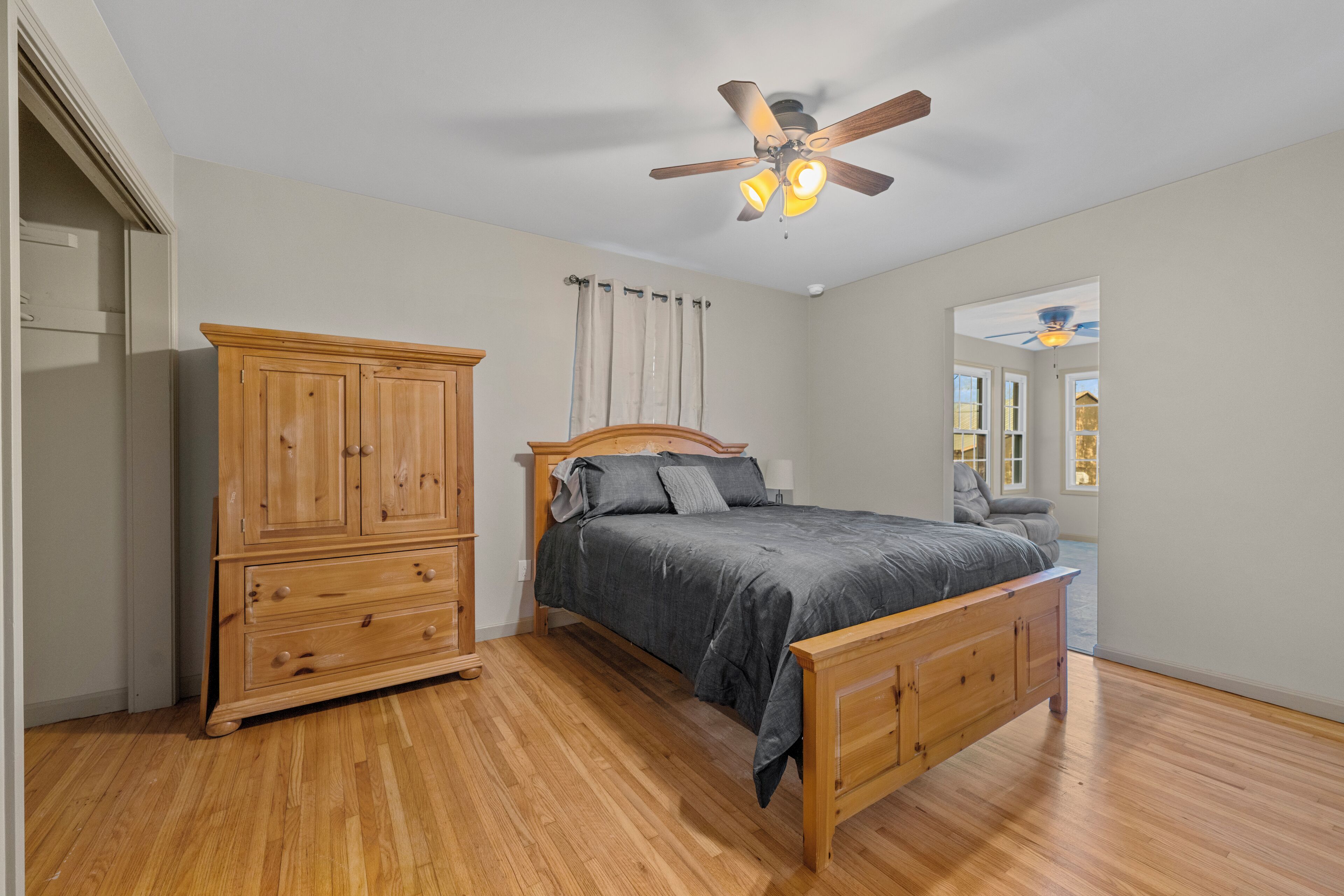 A bedroom with a wooden bed, a nightstand, a wardrobe, and a ceiling fan.