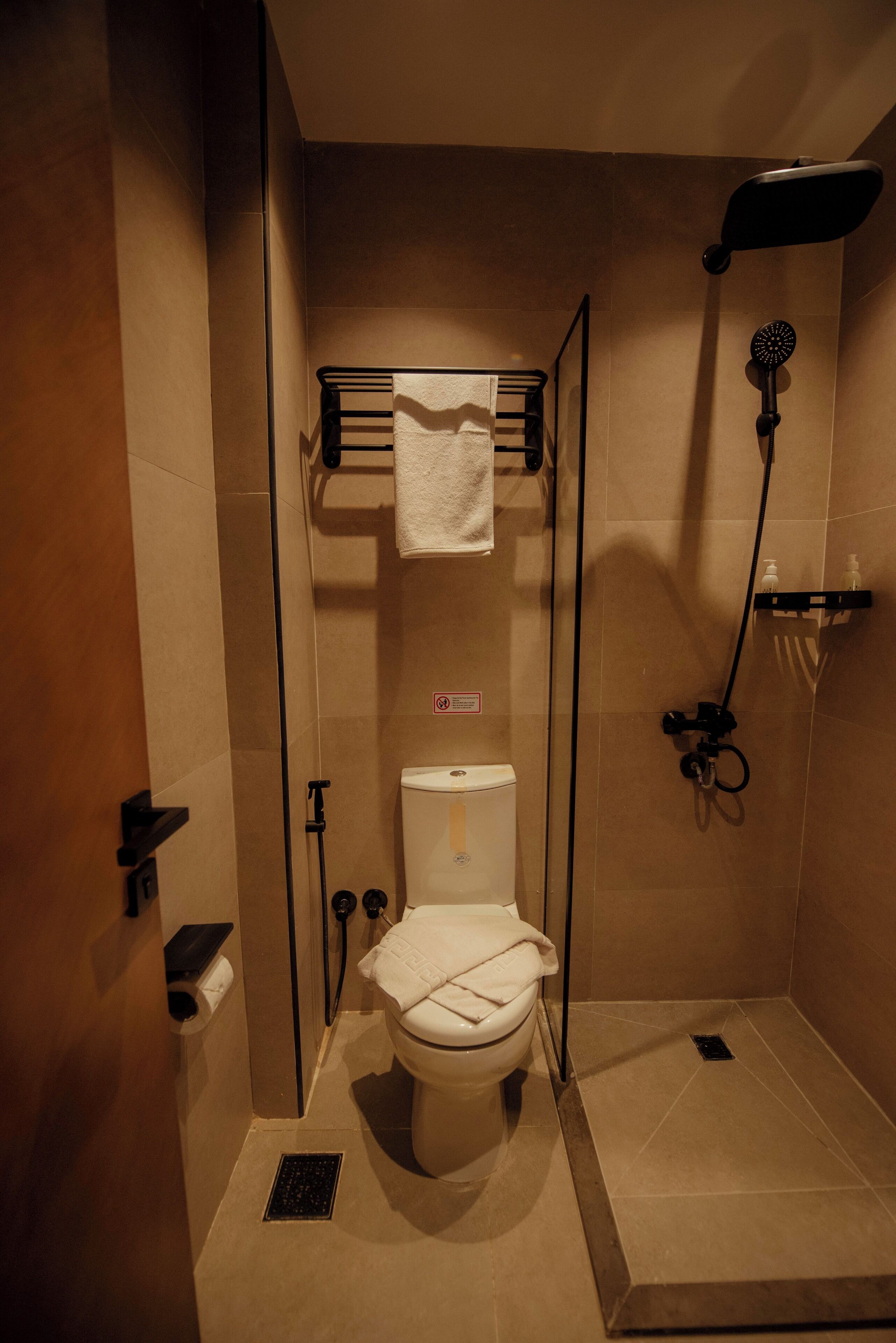 A compact bathroom with a glass-enclosed shower, a toilet, and a towel rack.