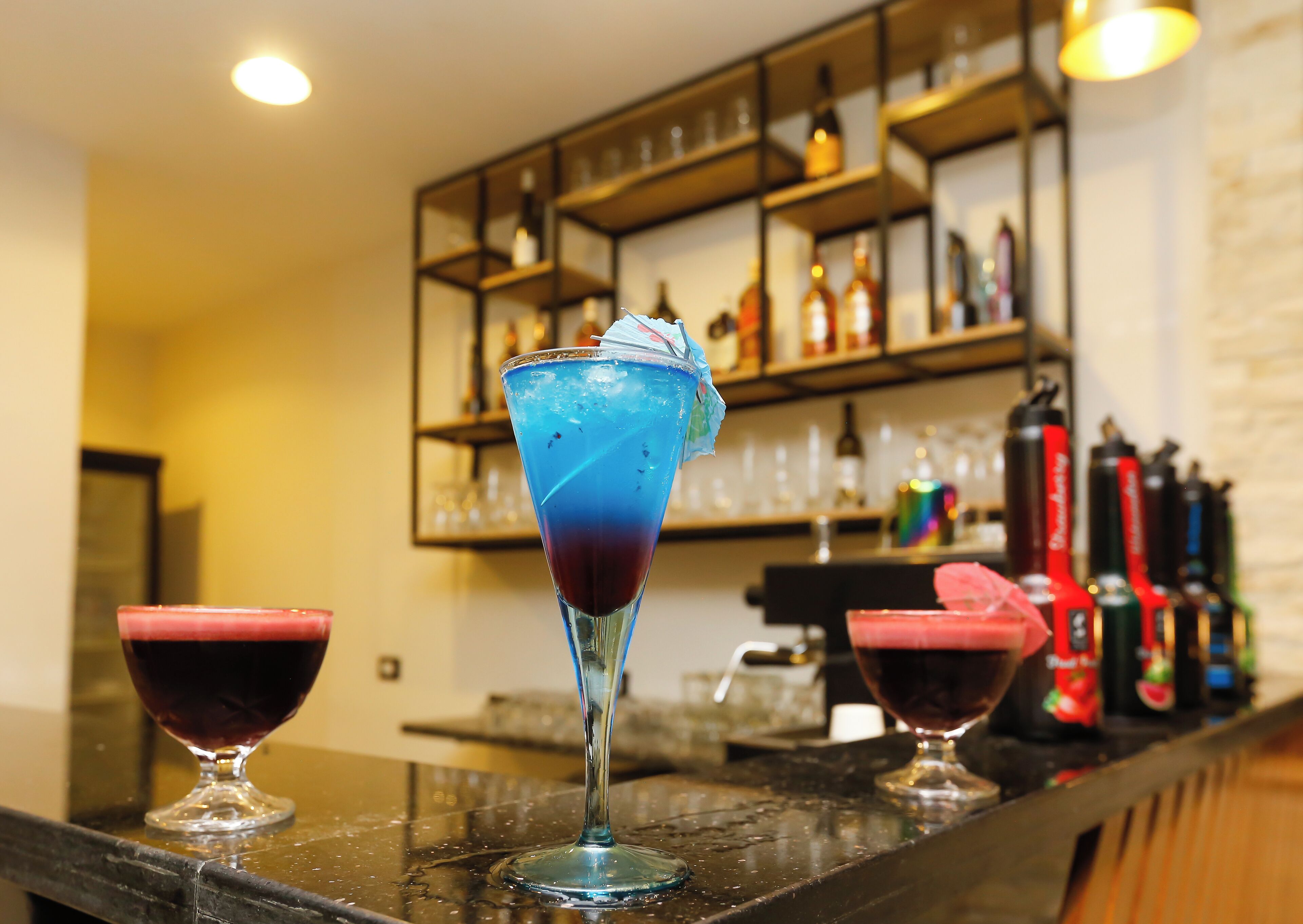 A bar area with a counter displaying various bottles and glasses.