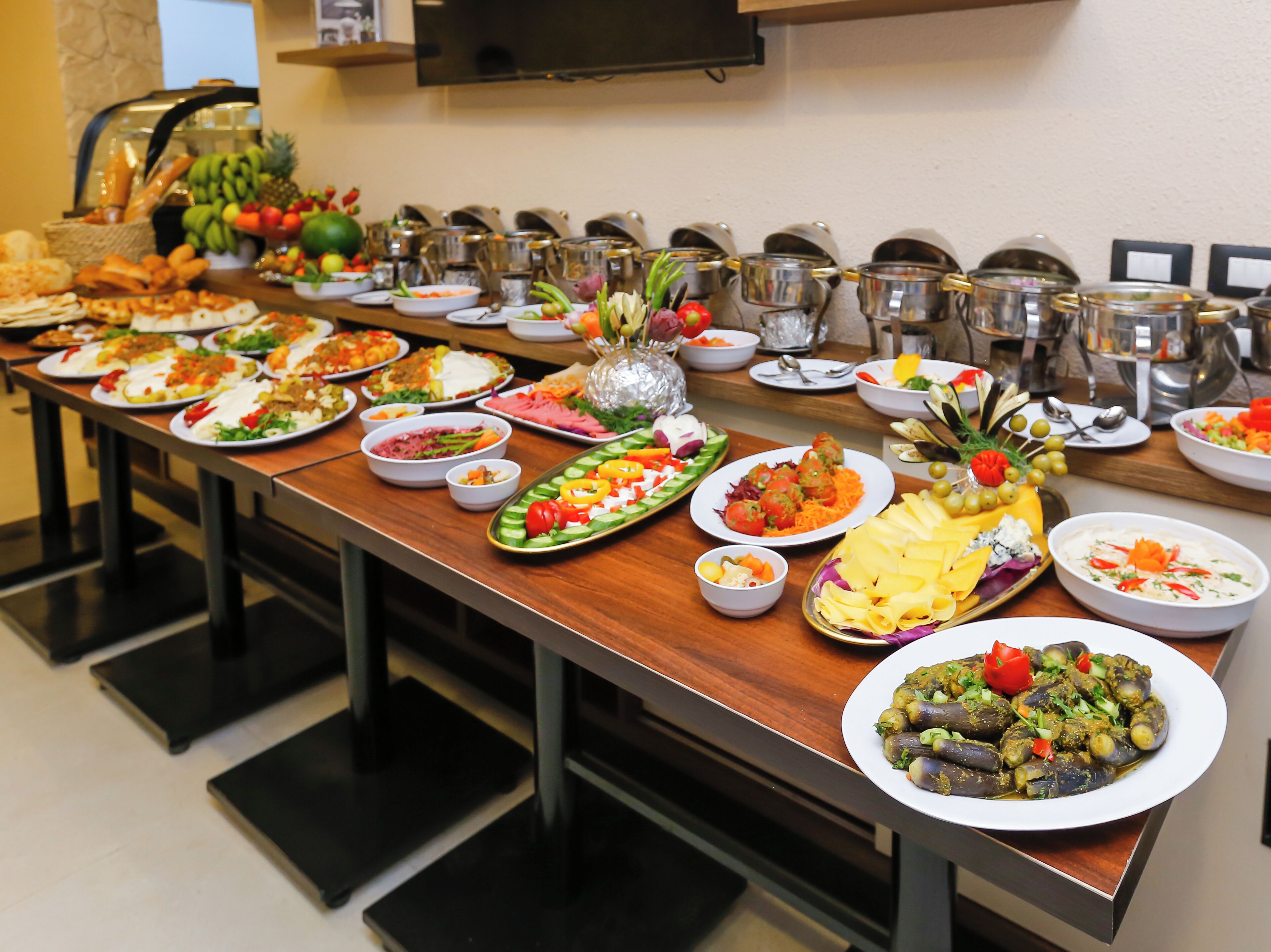Une table de buffet garnie de différents plats et un téléviseur fixé au mur.