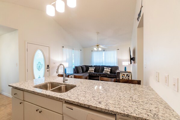A kitchen with granite countertops, a double sink, and a ceiling fan.