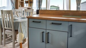 A kitchen with a wooden countertop, a dining table with chairs, and a window with curtains. - 3 bedroom accommodation in Lancaster (Lancaster)