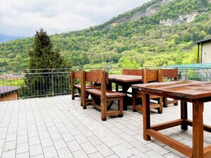 A terrace with wooden furniture and a view of a mountainous landscape.
