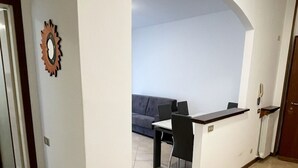 Uma sala de estar ampla com sofá, mesa de jantar e bancada de cozinha.