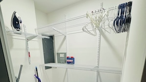 Una lavanderia con scaffali metallici, uno straccio, una scopa e un kit di pronto soccorso.