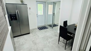Una cucina funzionale con frigorifero integrato, un'area pranzo con tavolo e sedie, e una porta che dà accesso a un'altra stanza.
