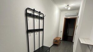 Een gang met een zwart metalen rek, een houten bank en een kleine tafel.