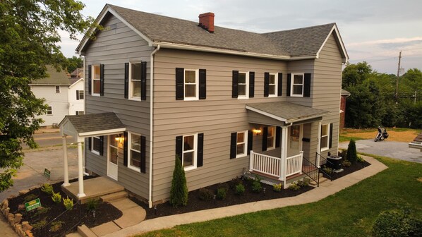 A two-story house with a covered porch, a chimney, and a well-maintained lawn.