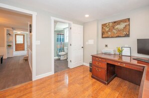 A room with a wooden desk, a printer, and a world map on the wall.