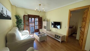 Un salon avec un canapé, une télévision et un plancher en bois.