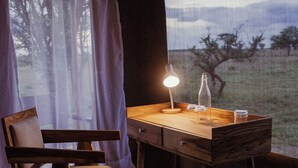A wooden desk with a lamp, a chair, and a bottle. - Conserve Safari Serengeti (Serengeti)