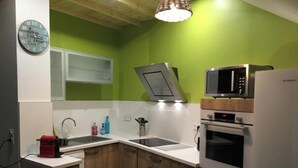 Una cocina compacta con microondas, horno y un reloj en la pared.