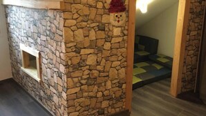 Una habitación con pared de piedra, una viga de madera y un ventanal pequeño.