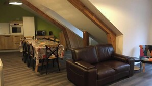Un espacio habitable tipo loft con comedor, un sofá de cuero y una cocina con vigas de madera.