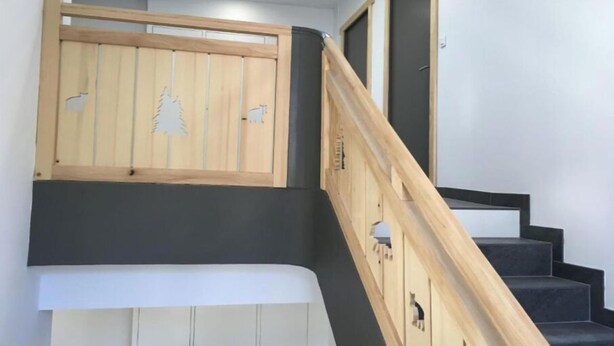 Una escalera con barandillas de madera y un panel de madera con un diseño de árbol y animales.