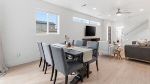 A spacious living room with a dining area, a flat-screen TV mounted on the wall, and a staircase leading to another level. - Modern Meridian Retreat - Spacious 4 Bedroom - Walkable Downtown (Meridian)