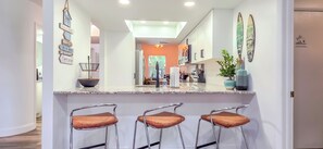 Une cuisine moderne dotée d’un îlot central, de tabourets de bar et donnant sur la salle à manger.