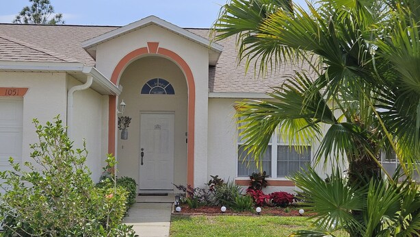 A single-story house with a front entrance, a small porch, and a well-maintained garden with various plants and flowers.